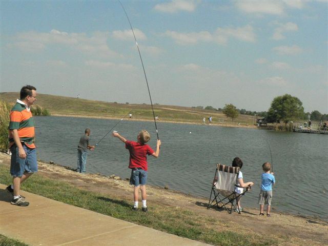 A man and a boy fishing together on a serene lake